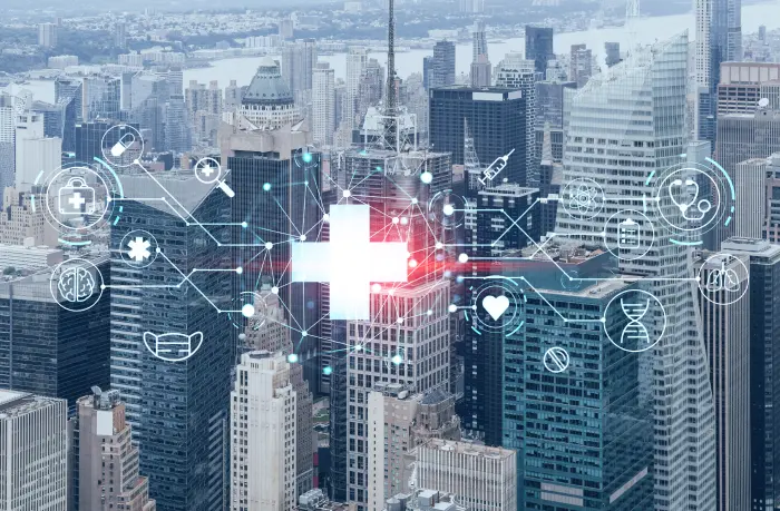 A digitally enhanced cityscape featuring various healthcare-themed icons such as a cross, stethoscope, syringe, DNA strand, and heart interconnected by lines hovers over the buildings, symbolizing the integration of technology and healthcare in urban settings and highlighting the need of a hospital management system.